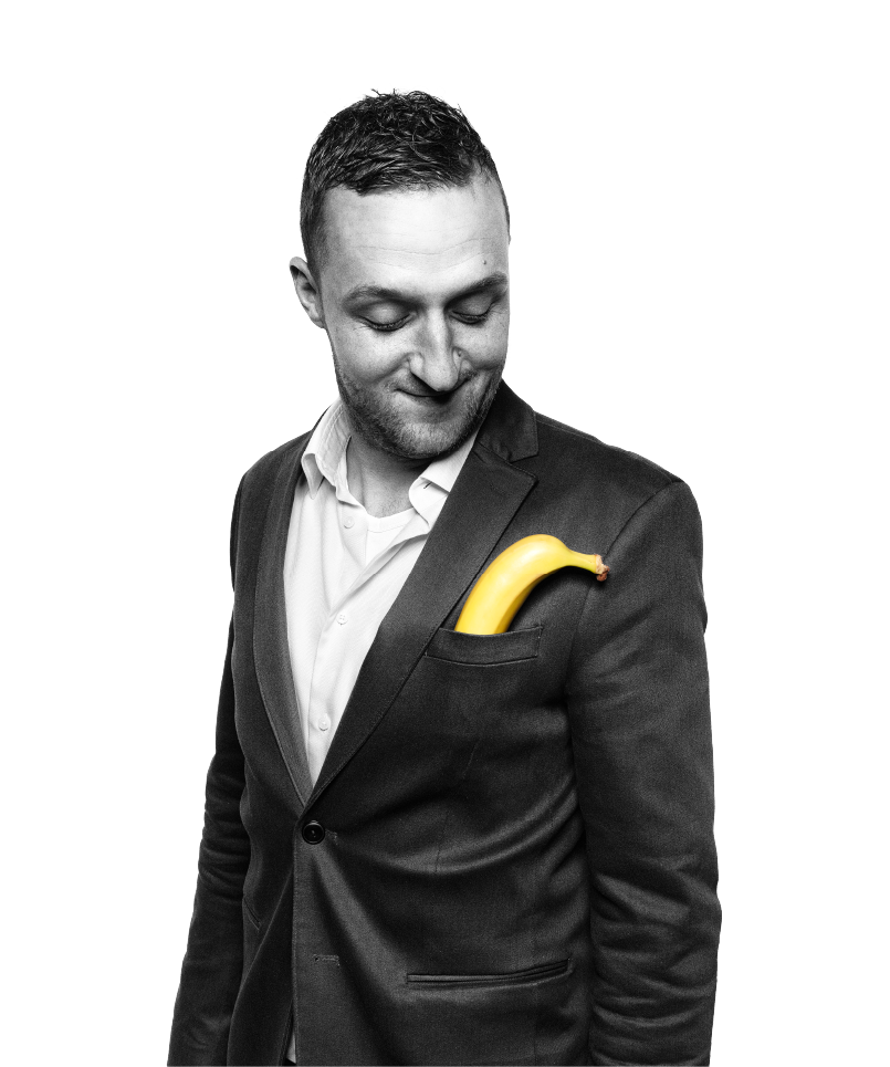 man kijkt naar beneden in pak en heeft een banaan in zijn borstzak