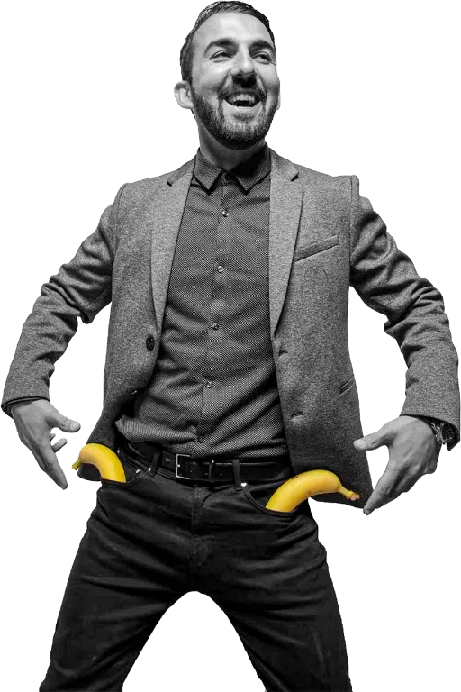 Lachende man in pak met twee bananen bij zijn broekzakken