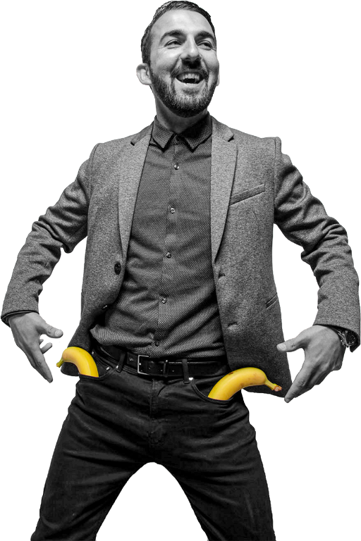 Lachende man in pak met twee bananen bij zijn broekzakken